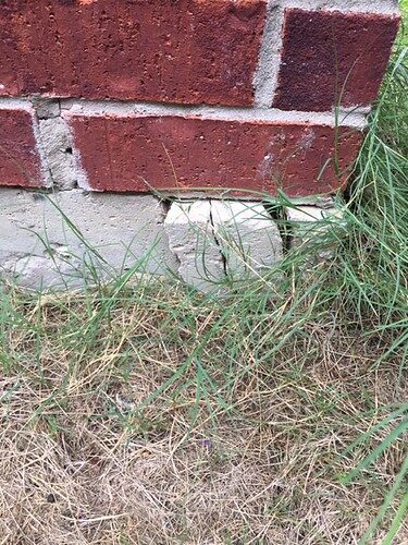 Cracked concrete slab edge below a brick wall, shown as an example of the settlement cracking foundation repair addresses